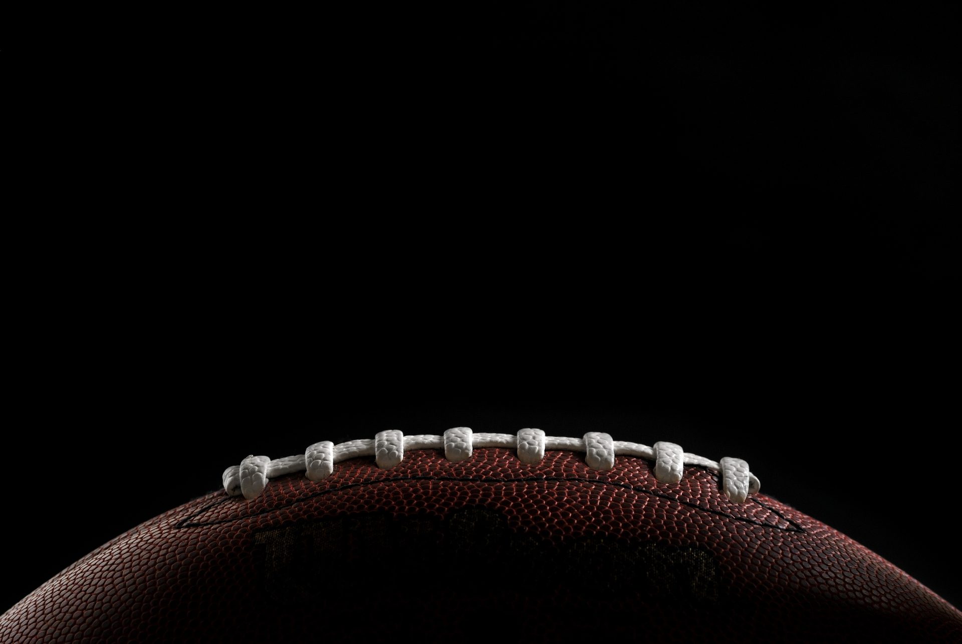 Close-up of an American football against a black background